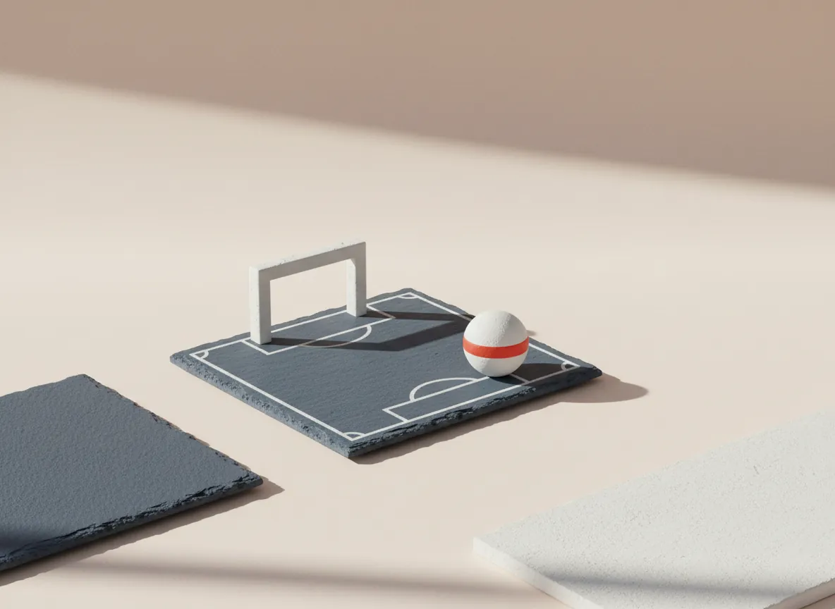 Still life: a small slate tile painted as a football pitch with a white goal and ball